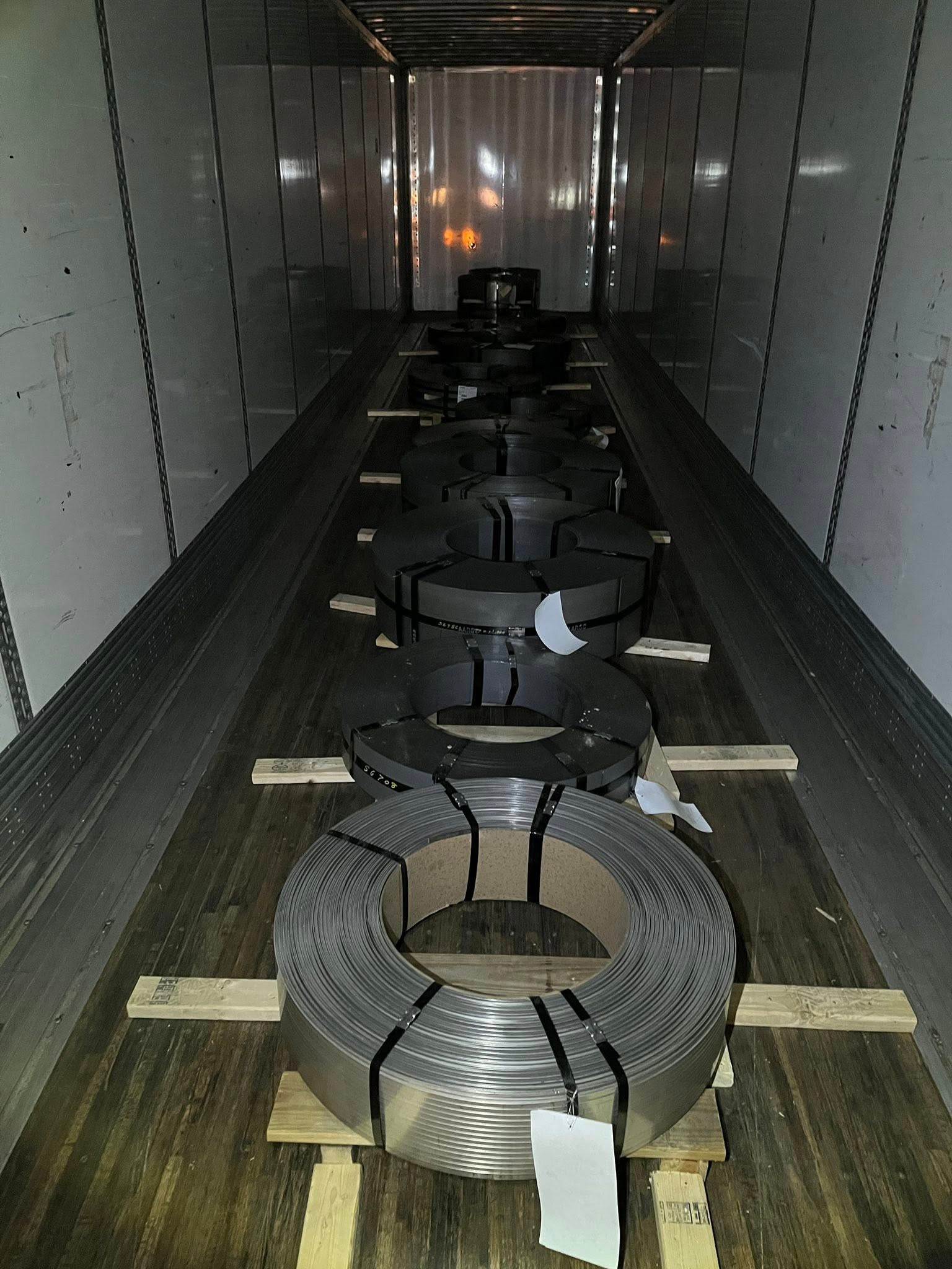 Coils repositioned along the wall, properly chocked and secured — cleared for out-gating